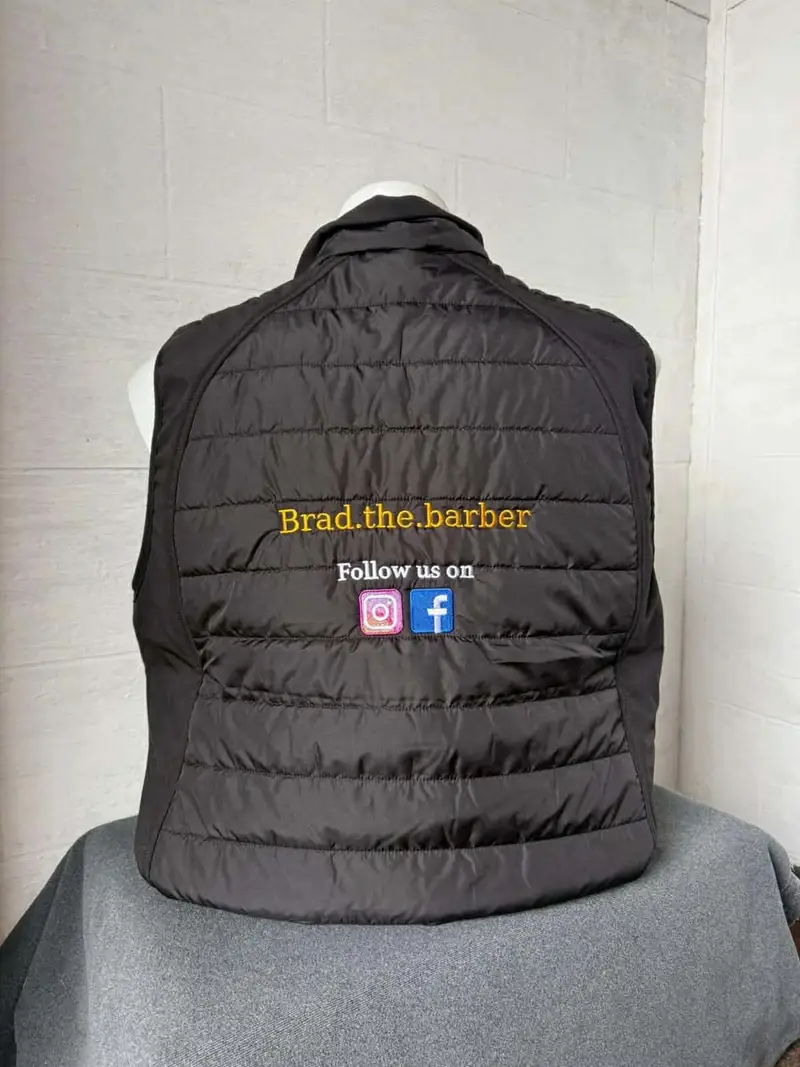 Black gilet embroidered with the Brad the barber logo and social icons