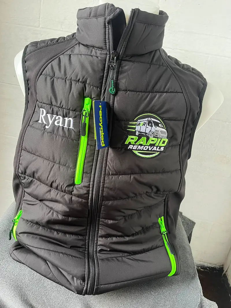 Black padded gilet embroidered in Colne with the Rapid Removals logo and the wearer's name, Ryan