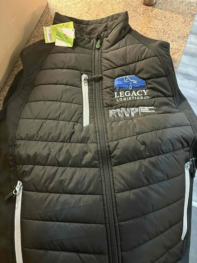 Black padded gilet embroidered with the Legacy Logistics van logo and a second sponsor mark