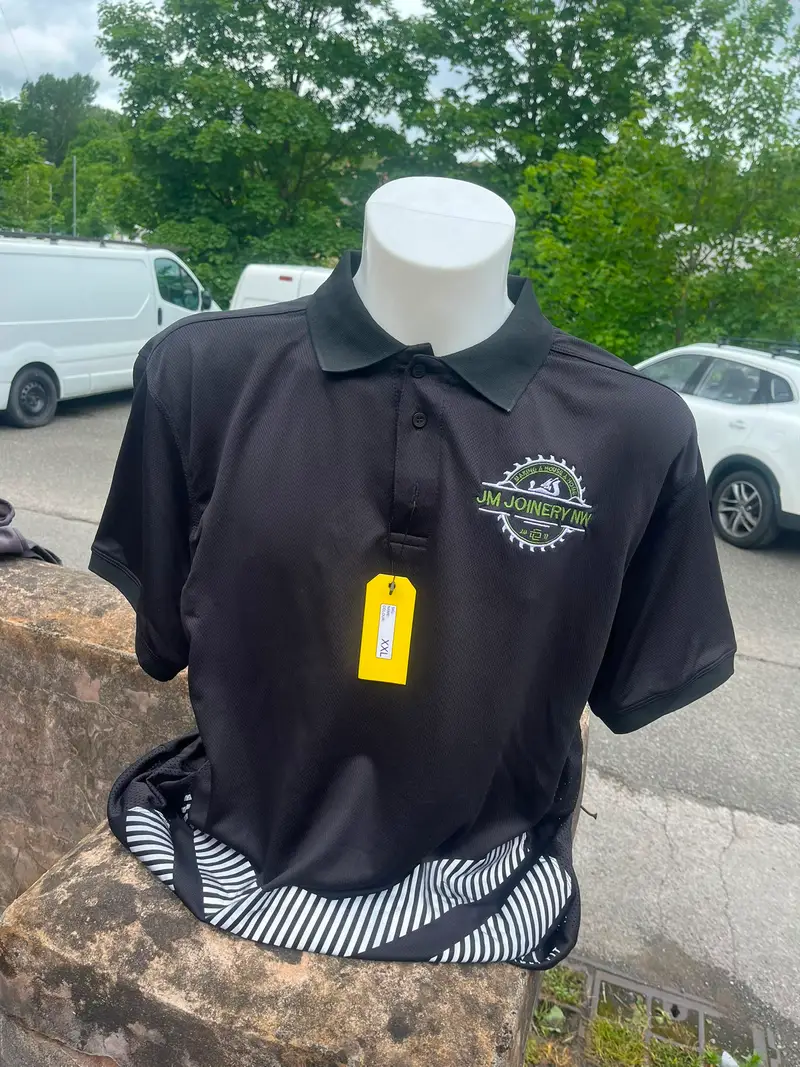 Black polo shirt embroidered with the JM Joinery NW logo