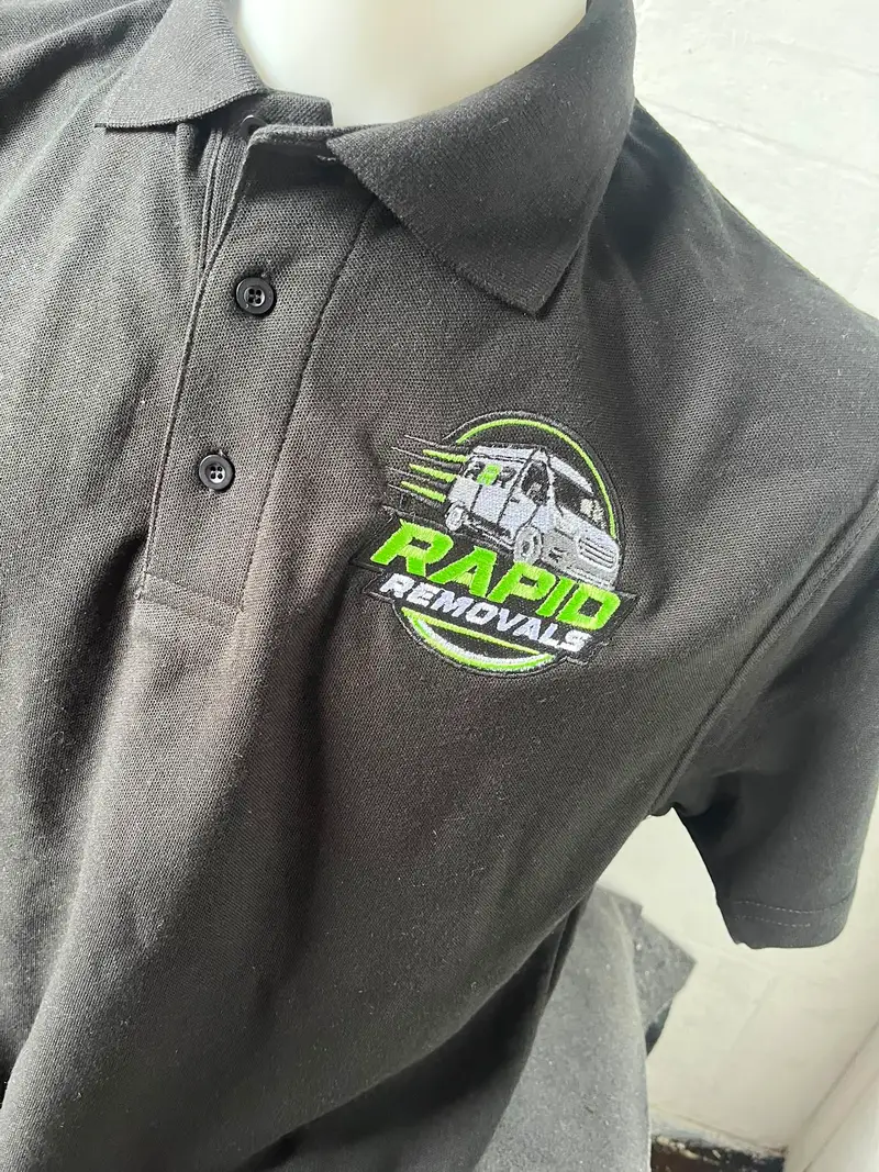 Black polo shirt embroidered with the Rapid Removals van logo