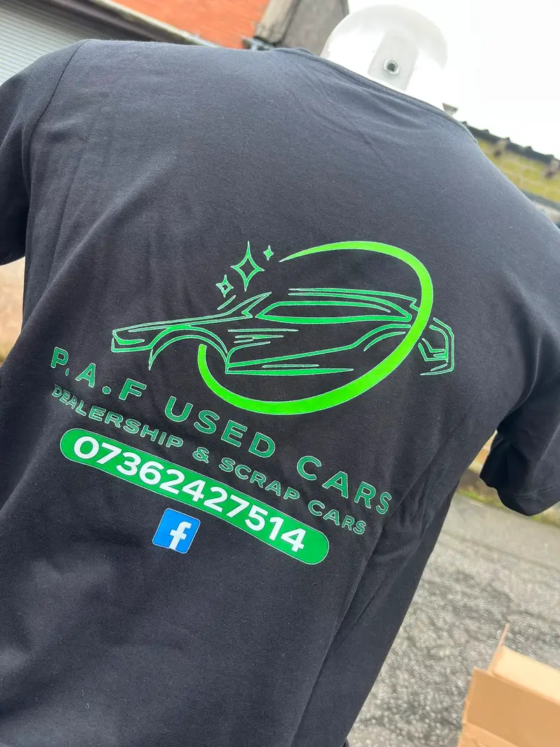 Black t-shirt printed with the P.A.F Used Cars logo on the back