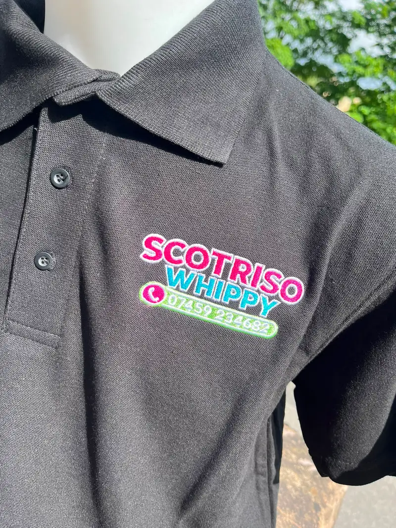 Close-up of the Scotriso Whippy logo embroidered in pink, blue and green on a black polo