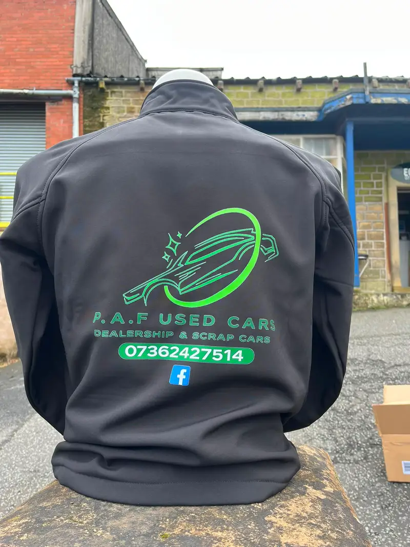 Dark jacket printed with a large green P.A.F Used Cars logo on the back