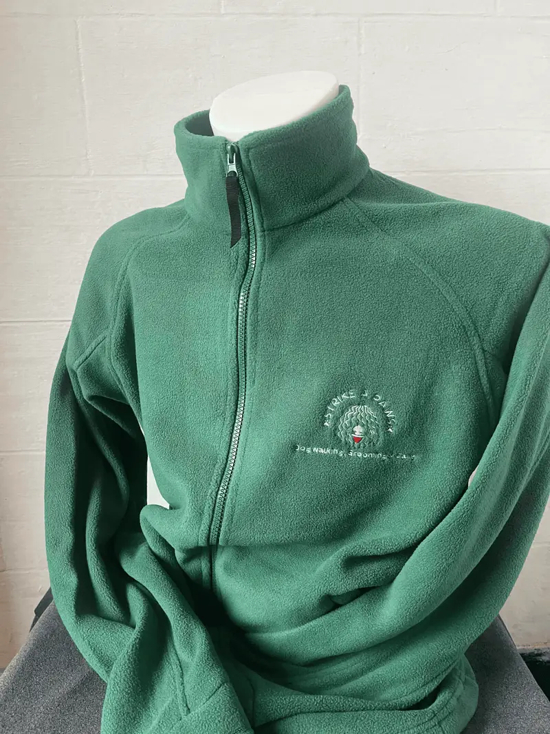 Green fleece jacket embroidered with the Strike A Paws logo