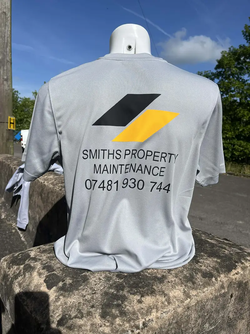 Grey t-shirt printed with the Smiths Property Maintenance logo and phone number on the back