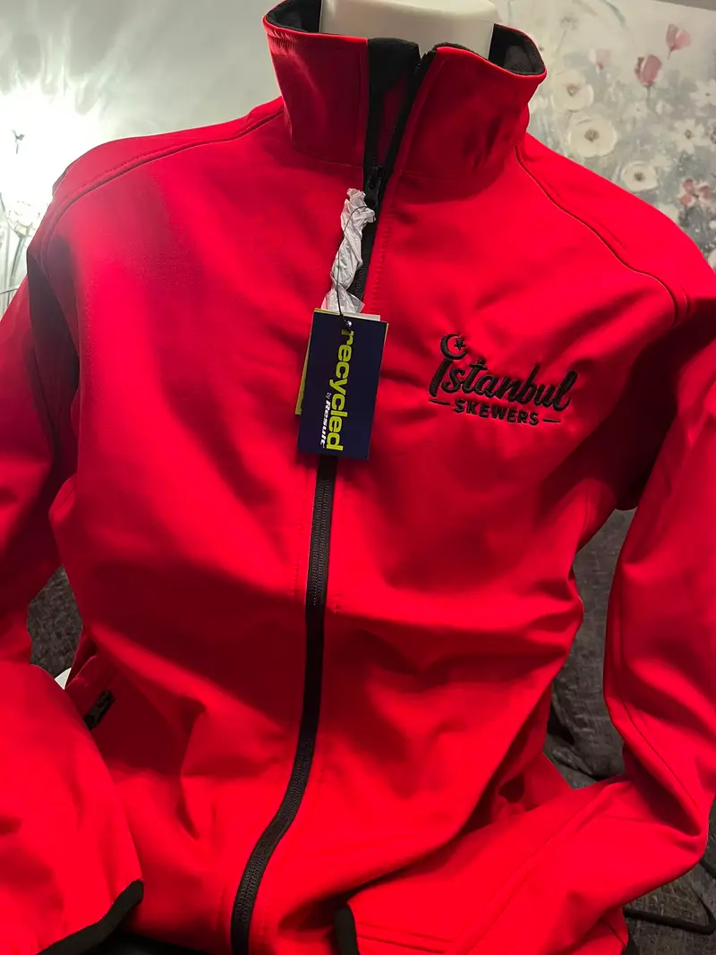 Red softshell jacket with the Istanbul Skewers logo embroidered on the chest