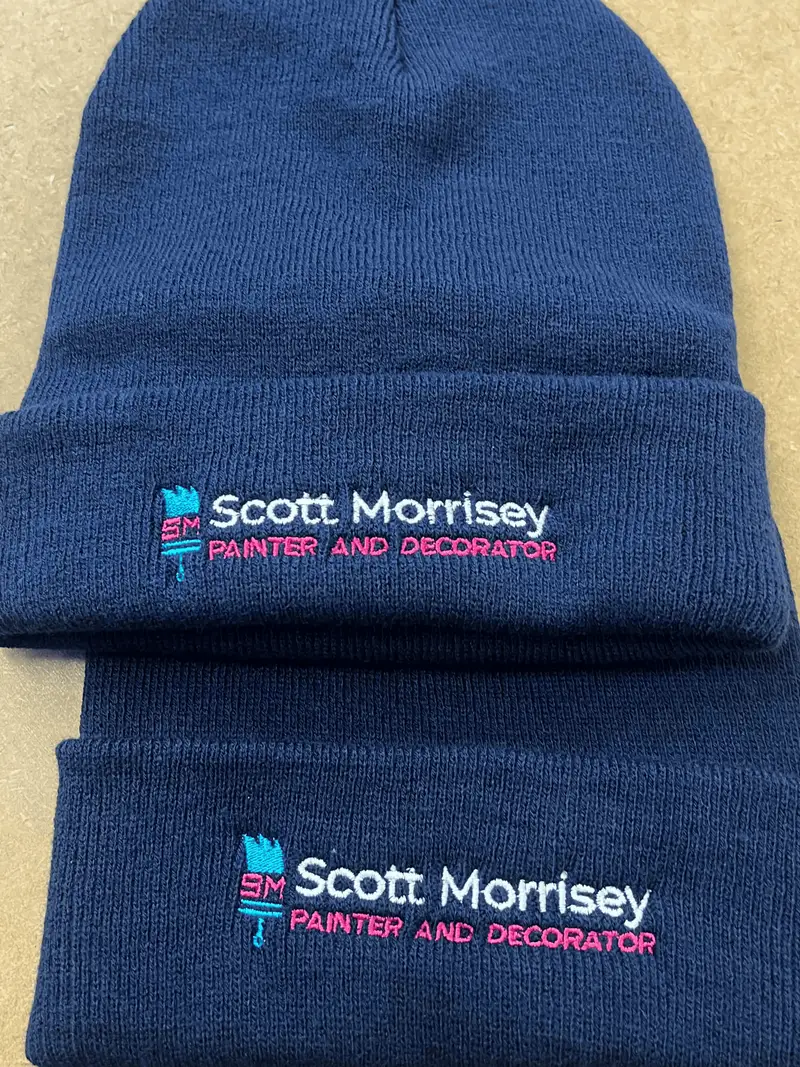 Two navy beanies embroidered with the Scott Morrisey painter and decorator logo