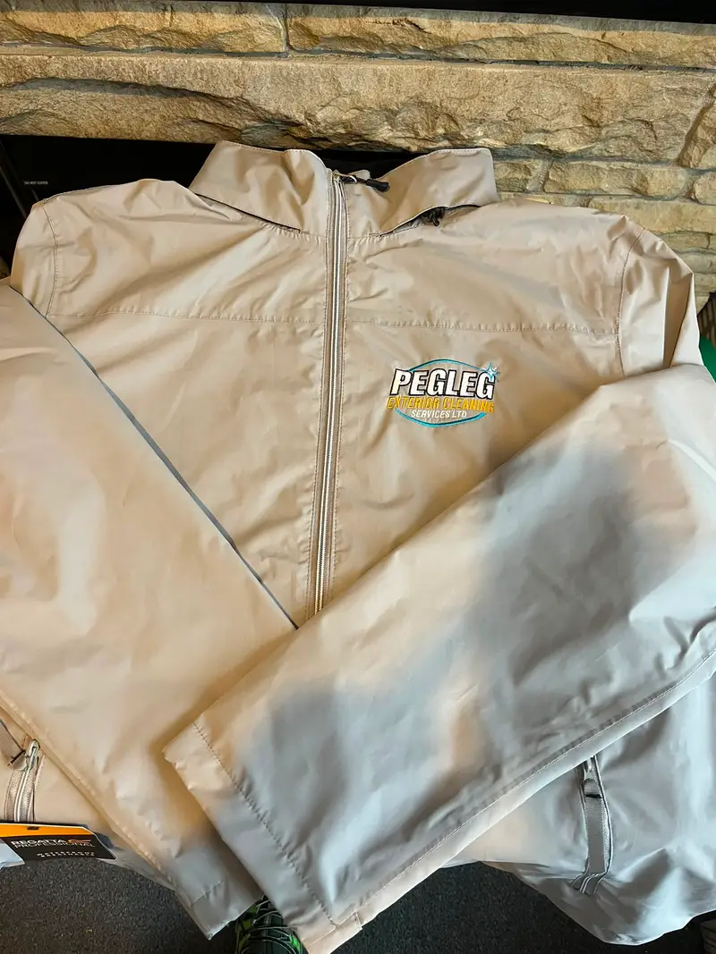 Two stone-coloured lightweight jackets embroidered with the Pegleg Exterior Cleaning logo